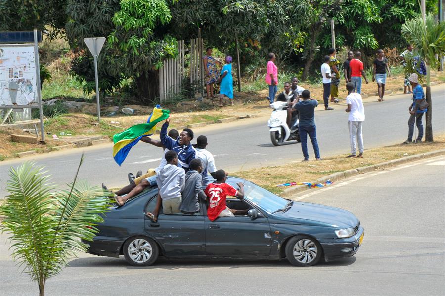 La gente ondea banderas nacionales de Gabón mientras celebran después de un golpe militar, en las calles de Akanda.