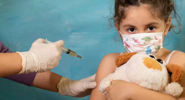 Una enfermera aplica una vacuna a un niño pequeño, simbolizando la importancia de la inmunización en la protección de la salud pública.