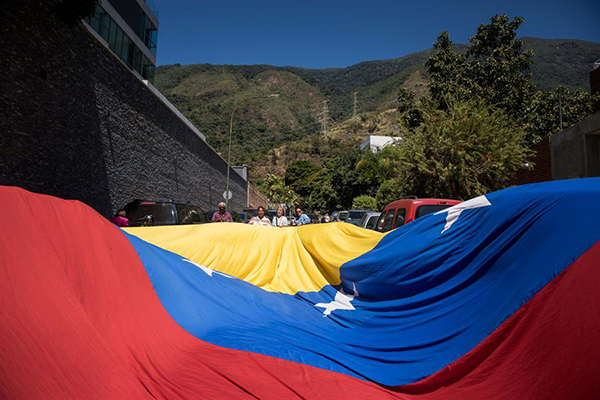 Simpatizantes de la líder opositora María Corina Machado ondean una bandera gigante venezolana durante un acto de calle, en Caracas.