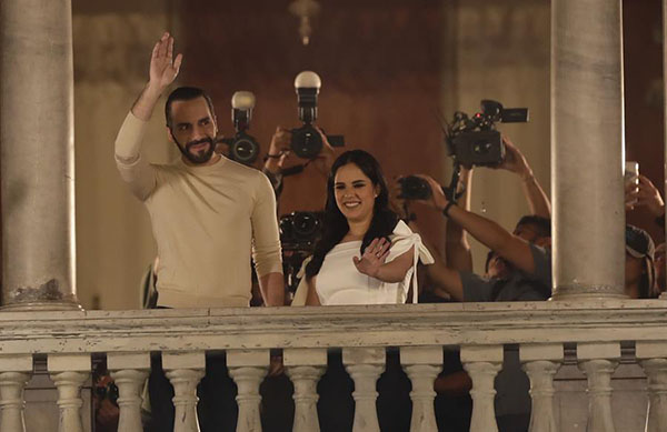 El actual presidente y ganador de la reelección en El Salvador, Nayib Bukele, saluda desde el Palacio Nacional junto a su esposa Gabriela Rodríguez de Bukele.