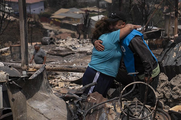 Personas se abrazan en una casa en el sector de Achupallas afectada por incendios forestales de Viña del Mar.