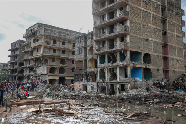 Un hombre se echa al hombro restos de la estructura de una vivienda en Mukuru, Nairobi, tras los efectos devastadores de las fuertes lluvias.