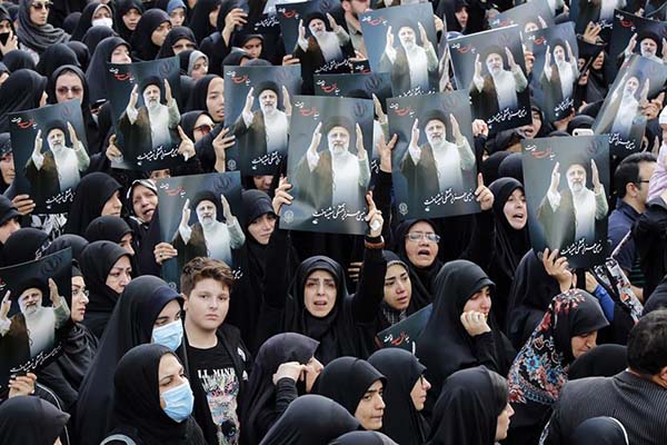 Mujeres iraníes vestidas con chadores negros sostienen carteles del difunto presidente mientras participan en una ceremonia de luto en Teherán. Mujeres iraníes vestidas con chadores negros sostienen carteles del difunto presidente mientras participan en una ceremonia de luto en Teherán.
