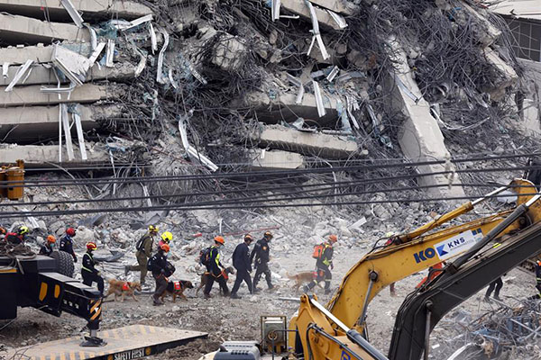Rescatistas con perros realizan una operación de búsqueda en el lugar del derrumbe de un edificio tras el terremoto.