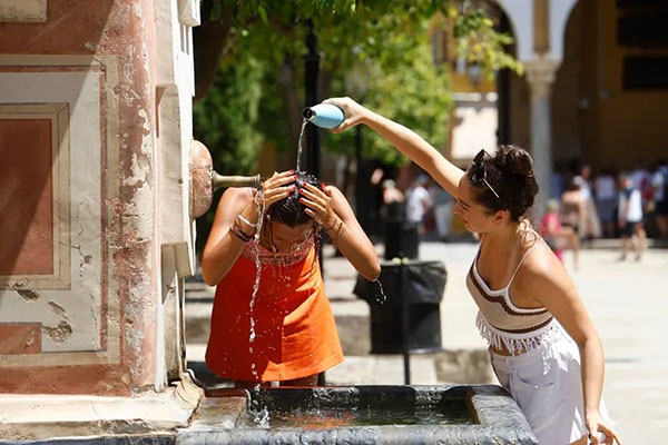 Dos mujeres se refrescan en una fuente del Patio de los Naranjos de la Mezquita Catedral de Córdoba. Archivo- EFE/Salas