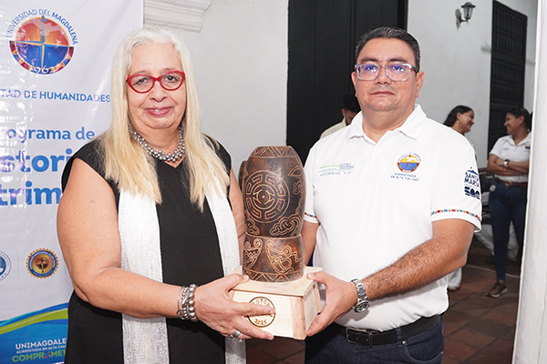 Patricia Moreno Linero, maestra y gestora teatral, recibiendo el reconocimiento por parte del doctor Adriano Guerra, director del Programa de Historia y Patrimonio. Foto Unimagdalena Patricia Moreno Linero, maestra y gestora teatral, recibiendo el reconocimiento por parte del doctor Adriano Guerra, director del Programa de Historia y Patrimonio. Foto Unimagdalena