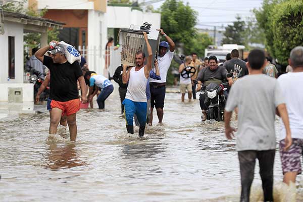 Personas intentan rescatar sus pertenencias este sábado luego de creciente del río Sinú, en Montería. Foto EFE
