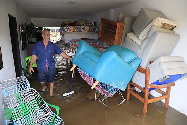 Un hombre alzó todas sus pertenencias para evitar que se mojen porque su casa está totalmente inundada en Lorica, Córdoba. Foto EFE