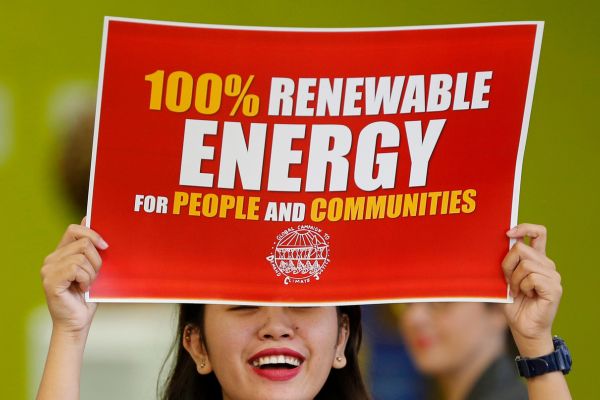 Una mujer sostiene un póster en el que se puede leer "energía 100 por cien renovable para las personas y las comunidades". Según datos de la Organización Latinoamericana y Caribeña de Energía, Olacde, América Latina y el Caribe es hoy la región más verde del mundo. (Foto EFE/Guillaume Horcajuelo)