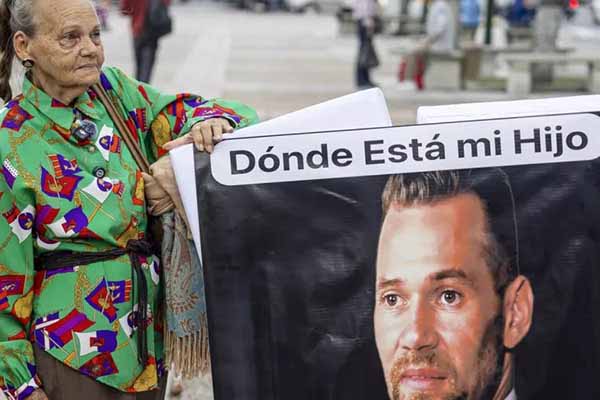 La madre de Víctor Quero Navas, sujeta un cartel cuando aún pensaba que su hijo estaba con vida. Foto EFE