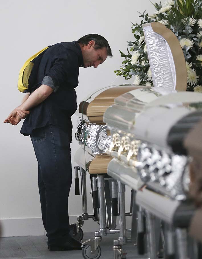 Roberto D’Marchi contempla el ataúd que contiene los restos de su primo de Nilson Folle Jr., víctima de la tragedia aérea colombiana, en el garaje de la funeraria de San Vicente en Medellín.