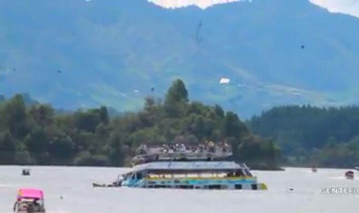 Los pasajeros se reúnen en la cubierta superior de 'El Almirante', el ferry que se hundió en las aguas del embalse de Guatapé.  Los buzos continuaron el lunes la búsqueda de cuerpos en la represa.