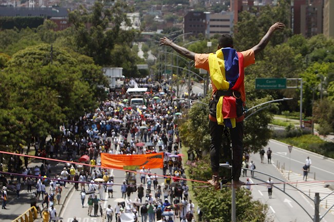 Un hombre realiza acrobacias frente a cientos de personas que marchan hoy durante una nueva jornada de protestas en el marco del Paro Nacional, en Medellín (Colombia). EFE 