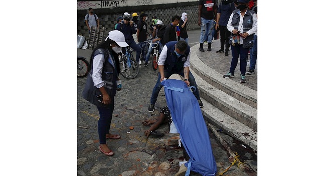 Miembros de la Defensoría del Pueblo de Colombia cubren a un hombre muerto en el suelo hoy, durante las manifestaciones en el sector La Luna, en Cali (Colombia).EFE