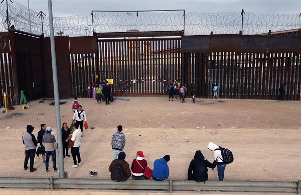 Grupos de migrantes hacen fila para cruzar a Estados Unidos y continuar con su proceso de asilo a través de la garita internacional del Chaparral en la fronteriza Tijuana.