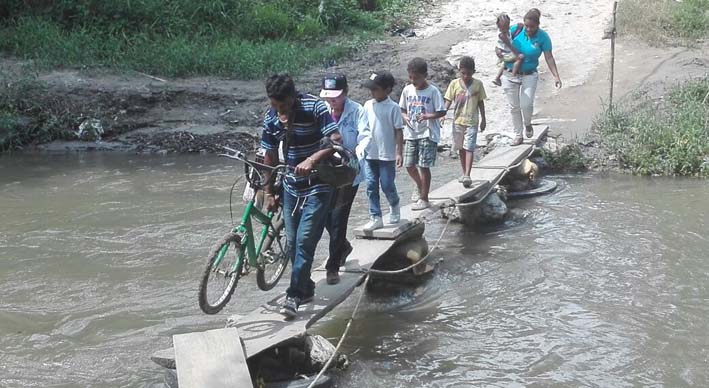 Uno tras otro, los niños atraviesan el peligroso ‘puentecito’ para salir del barrio Colinas del Río.