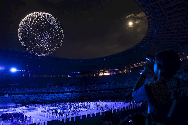 Un hombre fotografía los drones que forman un globo sobre el cielo durante la ceremonia de apertura de los Juegos Olímpicos de Tokio, en el Estadio Olímpico, hoy 23 de Julio de 2021. EFE