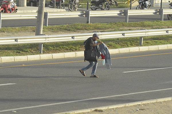 Afanado y con incomodidad por los elementos que sostiene, un peatón se mete por la doble calzada a la altura del barrio Santa Ana. 