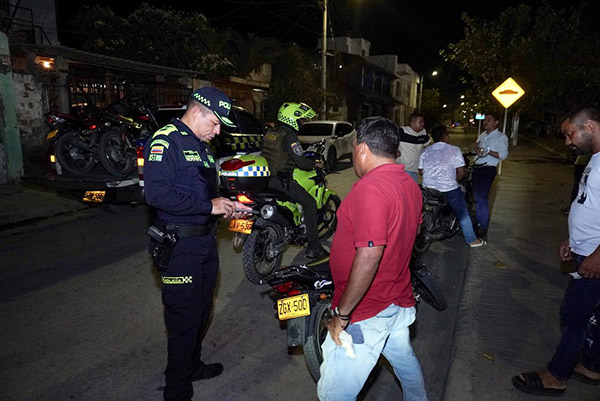 La foto muestra a un agente de la Policía Metropolitana inmovilizando una motocicleta por incumplir la medida de prohibición del parrillero hombre en el municipio de Ciénaga, Magdalena. 