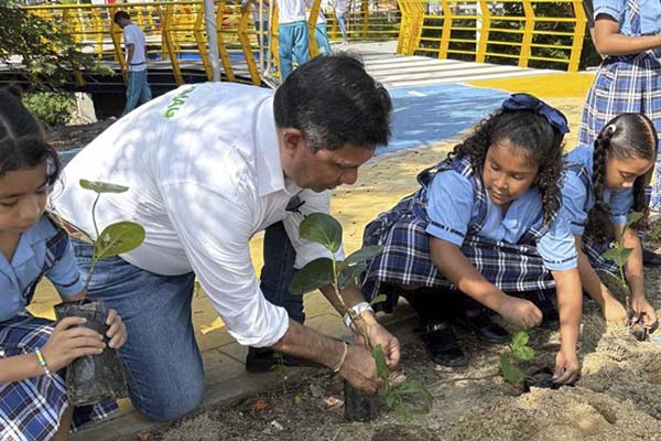 Alfredo Martínez Gutiérrez en compañía de niñas del IED Liceo del Sur en la jornada de siembra de árboles de ‘uvita de playa’ en el parque del río Manzanares. Foto Corpamag