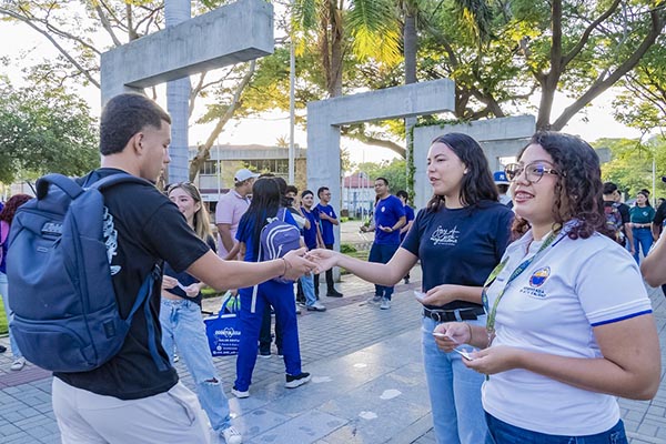 Una estudiante antigua y una funcionaria de Unimagdalena entregándoles galletas de la fortuna con mensajes motivadores a los nuevos miembros de la institución. Foto Unimagdalena