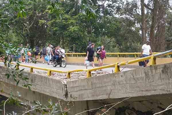 Turistas ponen en riesgo sus vidas al cruzar por la estructura colapsada del puente para poder realizar el trasbordo hacia su destino. A esta situación se suma el incremento en los costos del transporte, ya que deben pagar un pasaje desde Santa Marta hasta el punto de cruce y otro adicional desde el extremo opuesto para continuar su recorrido. Foto derechos reservados EL INFORMADOR