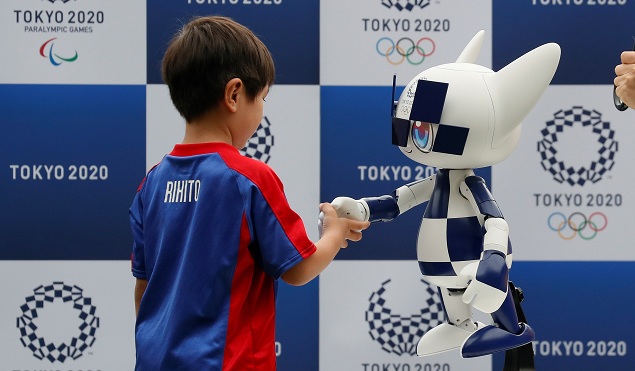 Un enfant serre la main de Miraitowa, la mascotte du robot des Jeux olympiques de Tokyo 2020.