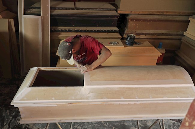 Un hombre trabaja armando y lijando un ataúd en el taller de una funeraria este miércoles en Managua (Nicaragua). EFE