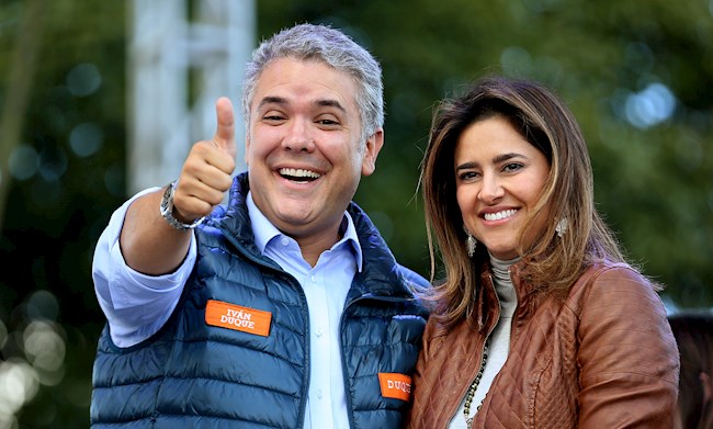 Fotografía de archivo que muestra a Iván Duque (i) quien saluda acompañado por su esposa, María Juliana Ruíz (d), durante su cierre de campaña el 20 de mayo de 2018, en Bogotá.