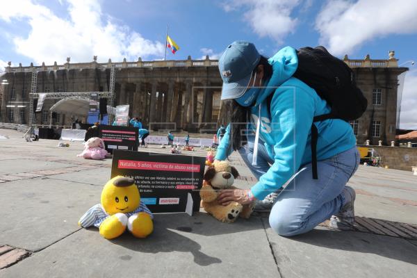 Una mujer acomoda letreros y juguetes en la Plaza de Bolívar como parte de una protesta realizada por la campaña "Soy Su Voz" de la organización internacional Aldeas Infantiles SOS Colombia que rechaza que niños y niñas violentados, sean separados de sus familias, hoy en Bogotá. EFE / Carlos Ortega