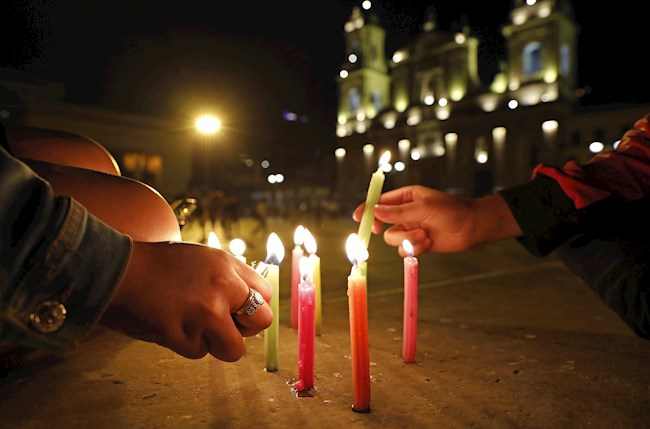 Una familia enciende velitas en la Plaza de Bolivar, en Bogotá.EFE