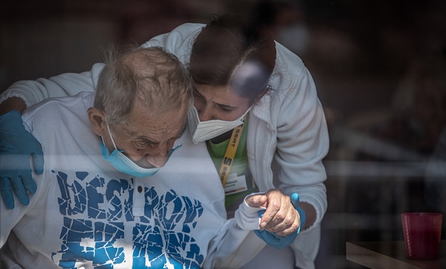 Un sanitario con mascarilla sostiene la mano de un residente de una casa de Alzheimer en Pitkovice, República Checa.
