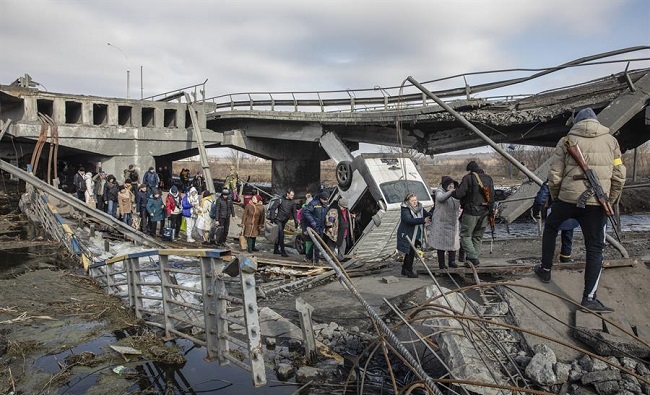 Los residentes cruzan el puente destruido mientras huyen de la ciudad de primera línea de Irpin, región de Kiev capital de  Ucrania.