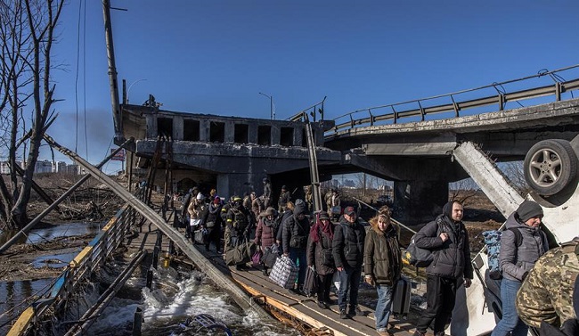 Residentes con su equipaje cruzan un puente destruido mientras huyen de la ciudad de primera línea de Irpin, región de Kiev capital de Ucrania.