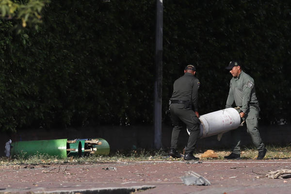 Policías mueven cilindros hallados en la zona del atentado tras una explosión en inmediaciones de la Escuela Militar de Aviación Marco Fidel Suárez este jueves, en Cali (Colombia). Al menos cinco personas murieron y 36 resultaron heridas por un atentado perpetrado con un camión bomba. EFE/ Ernesto Guzmán Jr