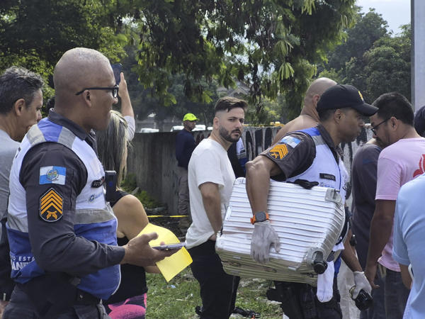 Fotografía cedida este domingo por Roberta Durço que muestra a un policía militar transportando una maleta recuperada en el lugar donde ocurrió el accidente de dos helicópteros en el barrio Recreio dos Bandeirantes, en Río de Janeiro (Brasil). Una de las aeronaves se incendió tras caer dentro de un estacionamiento privado y el fuego destruyó a unos veinte automóviles eléctricos que se encontraban estacionados en el lugar. EFE/ Roberta Durço