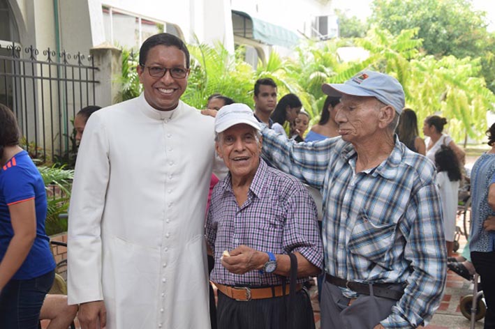 El padre Mario González García, director administrativo del CBA, junto a dos abuelitos.
