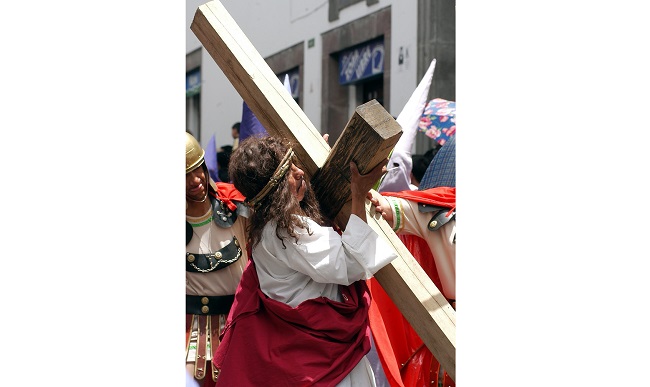 Un penitente representando a Cristo carga una pesada cruz, origen de todas las expresiones sobre llevar una cruz en la vida. EFE