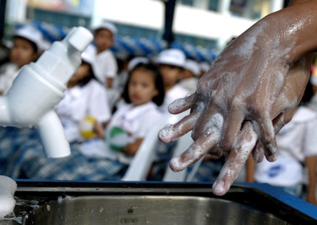 Vista a detalle de una persona mientras le enseña a los niños la forma correcta de lavarse las manos. EFE/