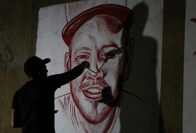 El artista Julián Castillo pinta un retrato del cantante puertorriqueño Residente con sangre humana, hoy, en el barrio Siloé, en Cali (Colombia).EFE