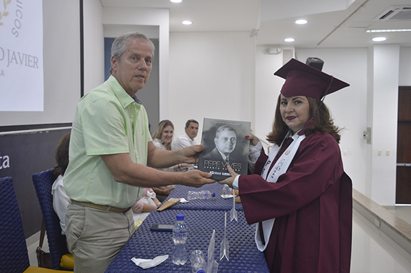 : Luis Vives entrega el libro ‘Pepe Vives: cuenta su vida’ a la graduada Sugey Picón. 