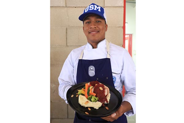 Uno de los estudiantes de la USM, que participó en la preparación de la receta del lomo navideño en salsa de furtos rojos.