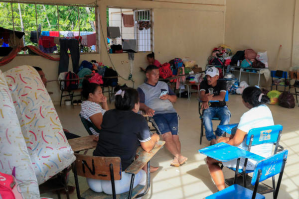 José Julián Castaño (c), damnificado por la creciente del río Sinú, habla con personas en un albergue transitorio en la institución educativa Las Delicias este jueves, en Tierralta, Córdoba (Colombia). En un salón de clases convertido en albergue temporal, con pupitres amontonados contra las paredes, colchones apoyados en los rincones y ropa tendida en las ventanas, José Julián Castaño mira su celular mientras espera noticias sobre cuándo podrá volver a su tierra.El campesino, padre de cinco niños, es uno de los EFE/ Carlos Ortega