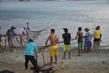 Un grupo de pescadores saca un chinchorro hacia la orilla de la playa al finalizar la tarde en Genemaka, Taganga.