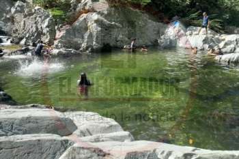 Una mujer registra con su teléfono una fotografía de la piscina natural más profunda de Quebrada Valencia mientras un grupo de personas disfruta del balneario y de las cascadas.  Fotos: Rony Barrera. Derechos Reservados/ELINFORMADOR